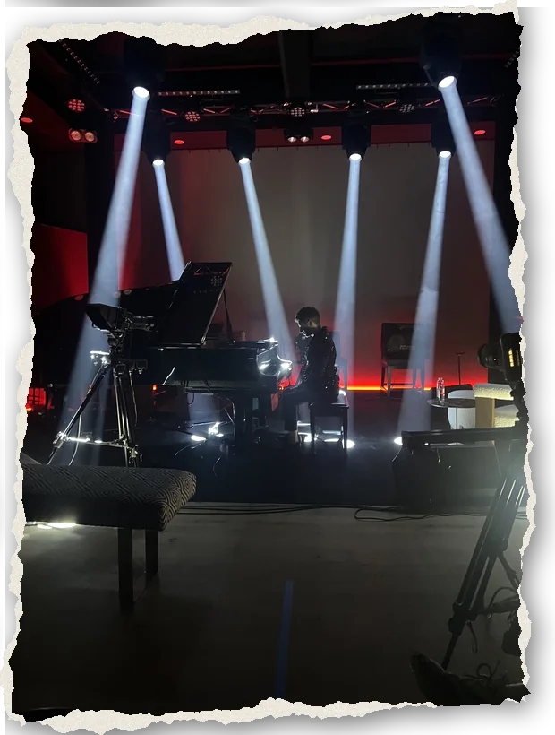 White light beams over the piano in the Live Room, with a cinema camera on the floor